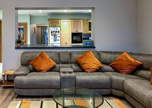 Couch with orange cushions and view to kitchen